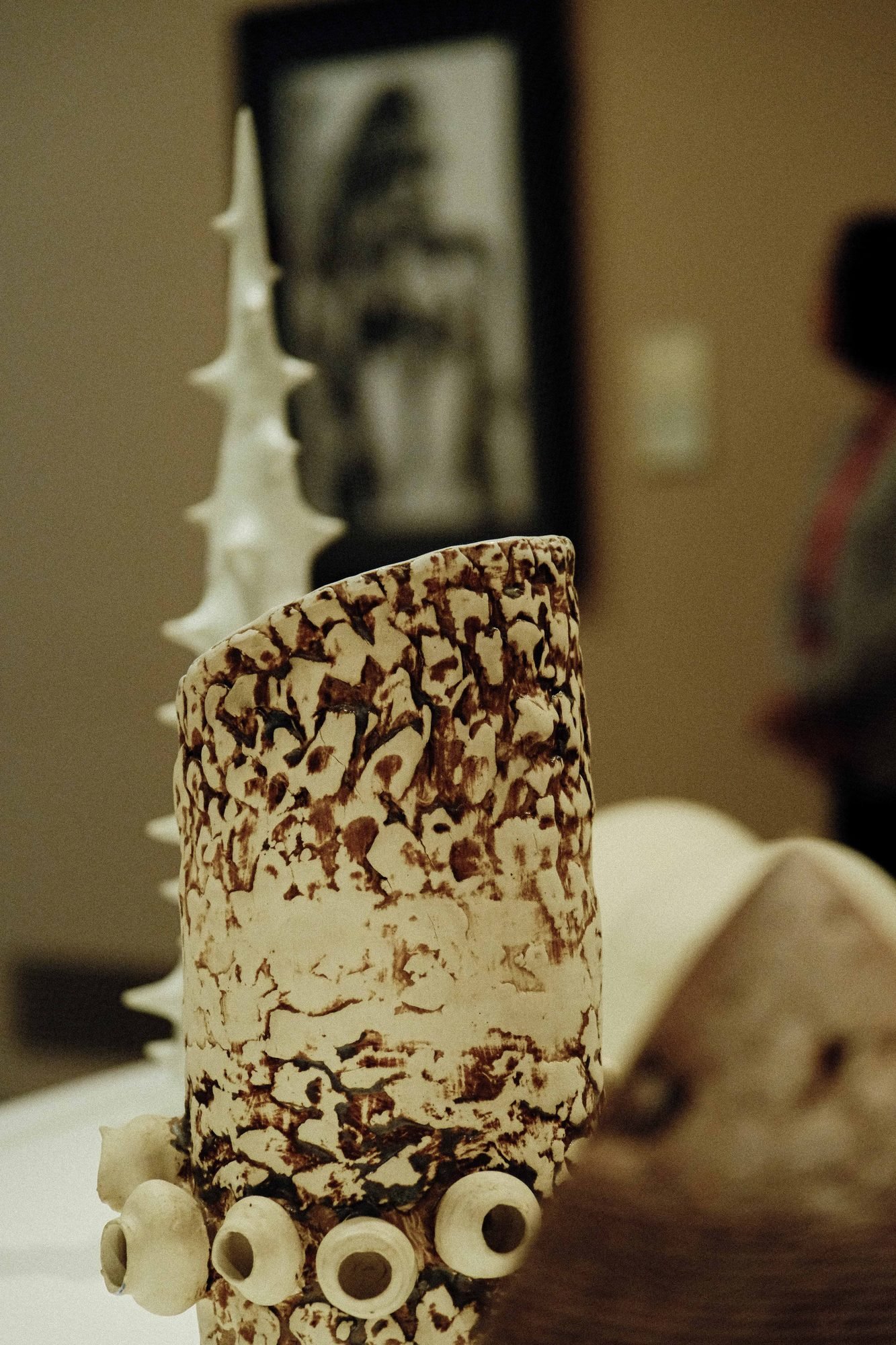 Textured ceramic sculpture rising against a warm orange wall