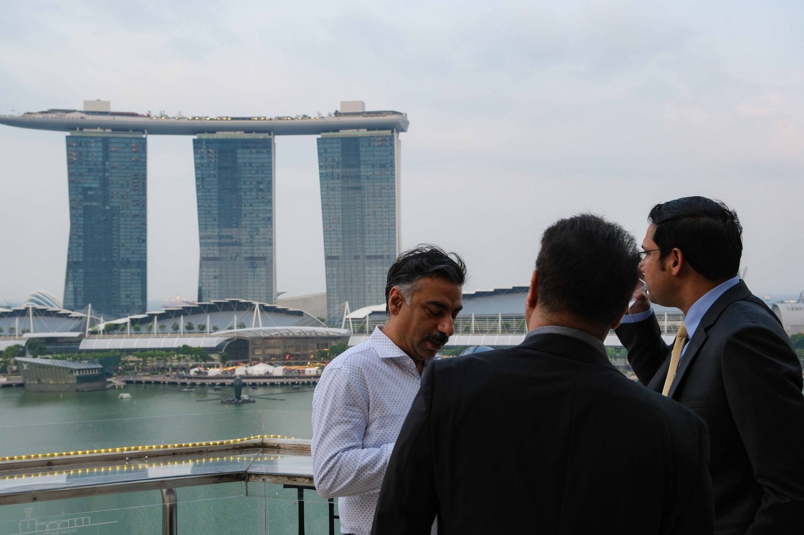 Guests mingling on a rooftop terrace with the marina skyline behind them