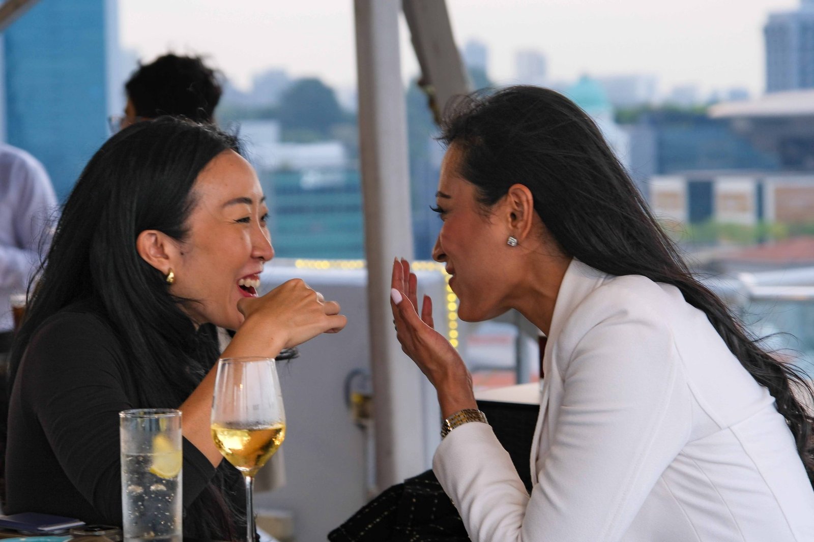 Two women laughing together at an evening networking event