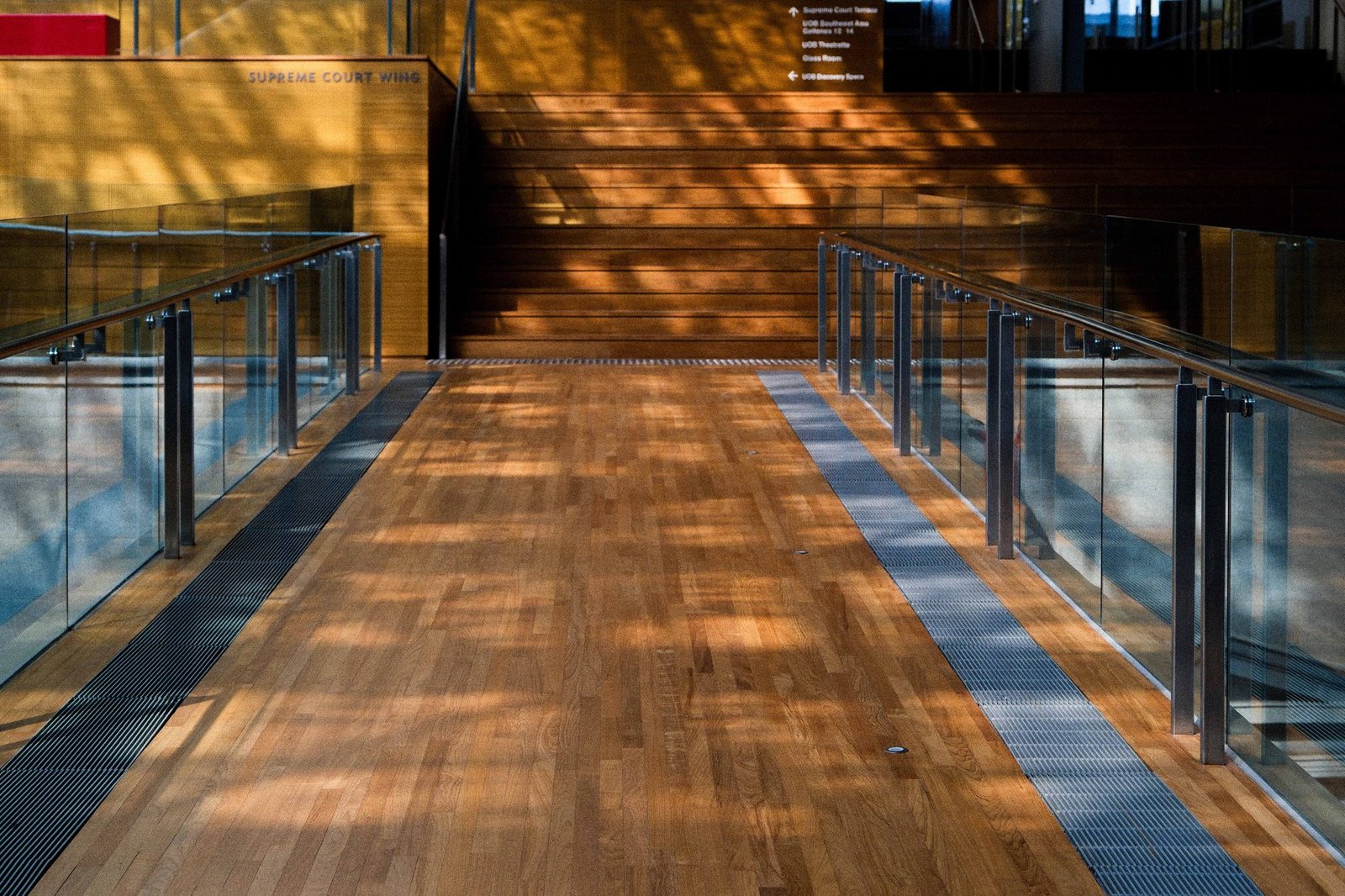 Sunlight streaming across a wooden walkway inside a modern atrium
