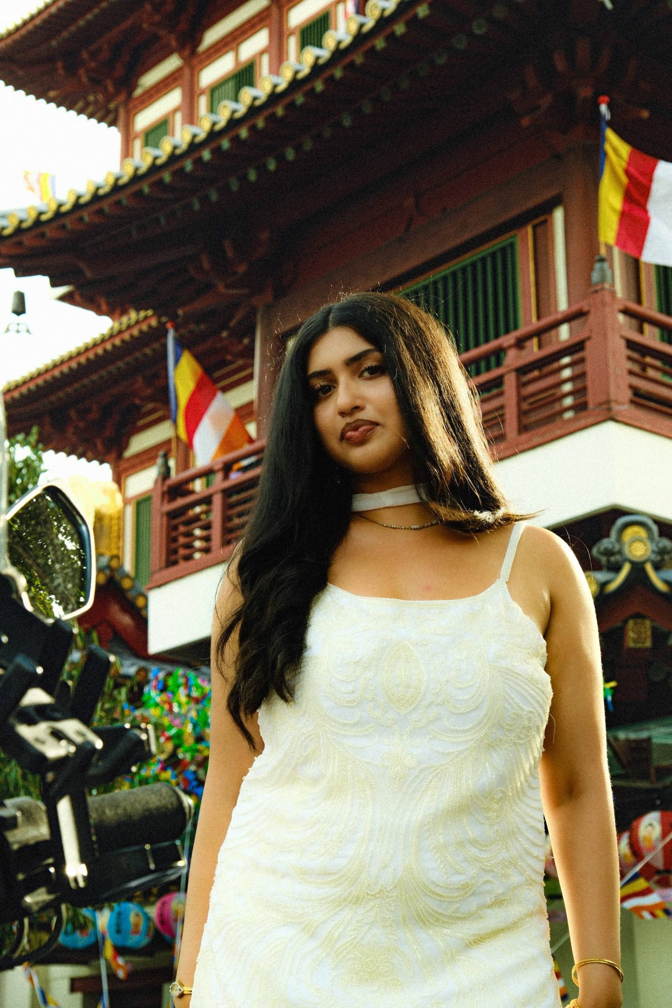 Woman in a white dress posing beside colorful lanterns on a shophouse balcony