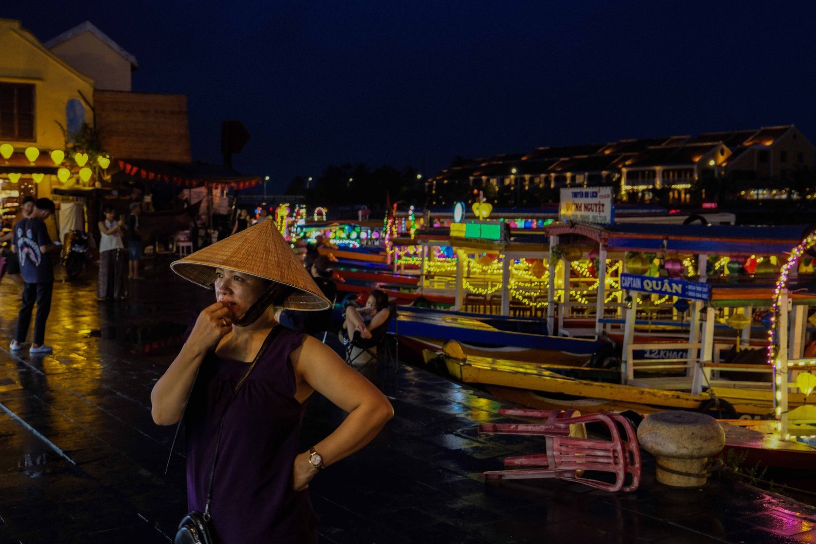 Colorful lanterns strung above a bustling Hoi An market street