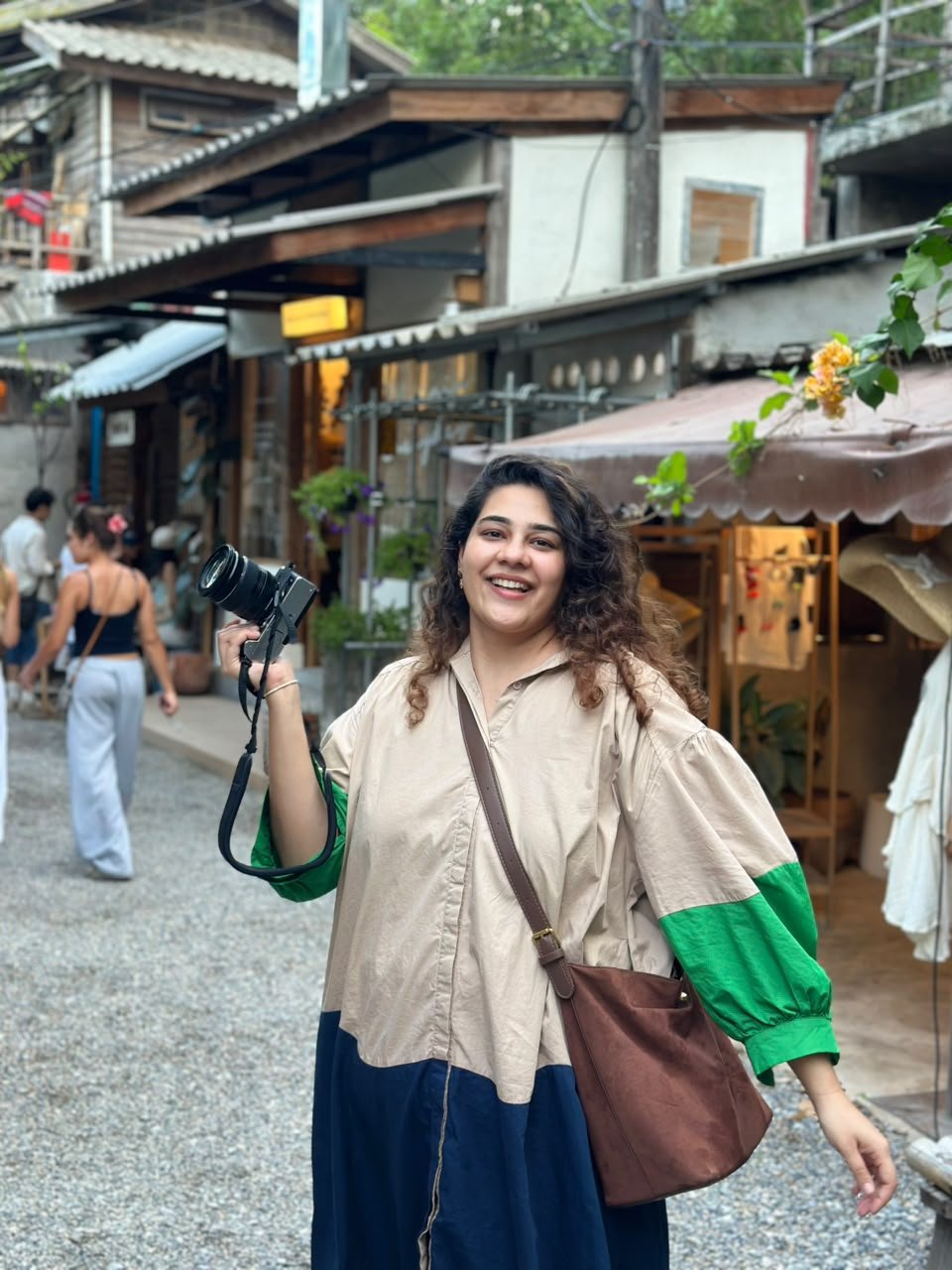 Divisha Bhatia smiling and holding her camera on a street in Japan